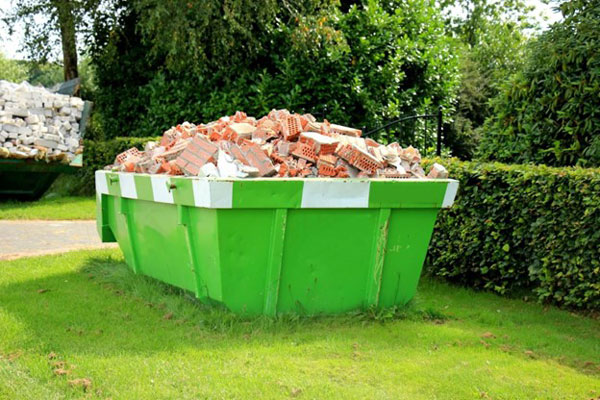 Green dumpster with broken bricks