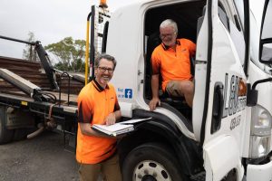 Two Workers Discussing Near a Skip Bin Truck in Central Coast